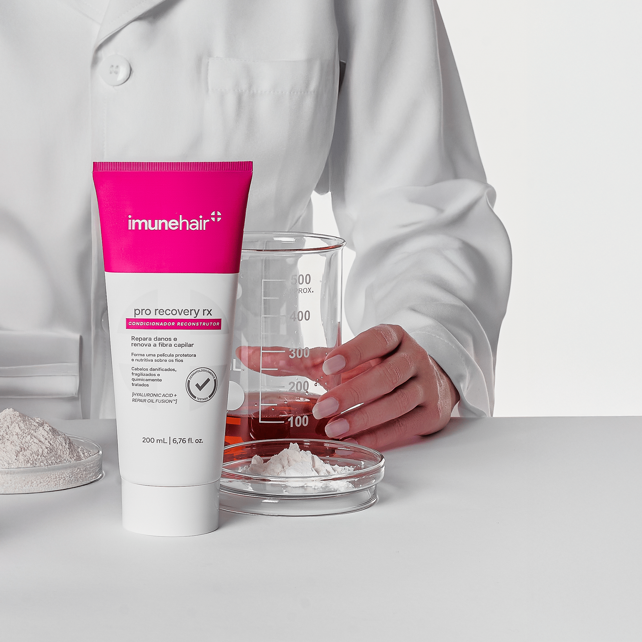 Embalagem rosa e branca do Condicionador Reconstrutor Pro Recovery RX com 200ml. Plaquetas e béquer com os ativos presentes na formulação do condicionador reconstrutor.