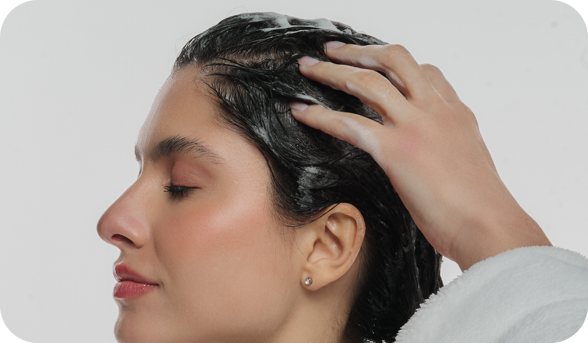 Mulher morena passando os dedos na raiz dos cabelos para ensinar como usar o Shampoo Anticaspa Scalp Relief corretamente.