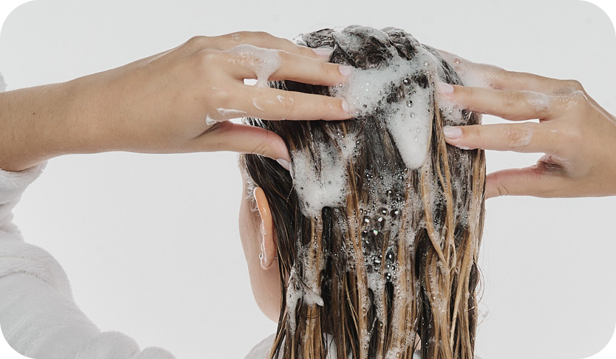 Mulher limpando o couro cabeludo com o Shampoo Antioleosidade Oil Balance, ensinando a melhor forma de usar o produto.