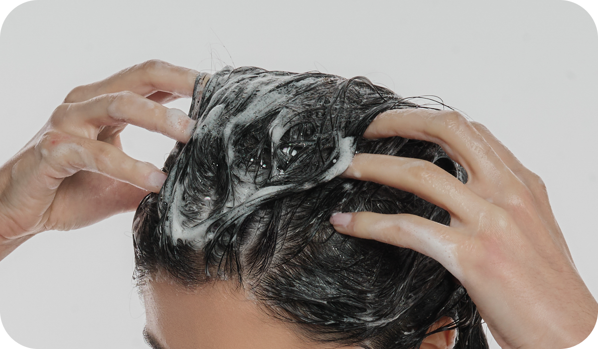 Mulher morena passando os dedos na raiz dos cabelos para ensinar como usar o Shampoo Anticaspa Scalp Relief corretamente.