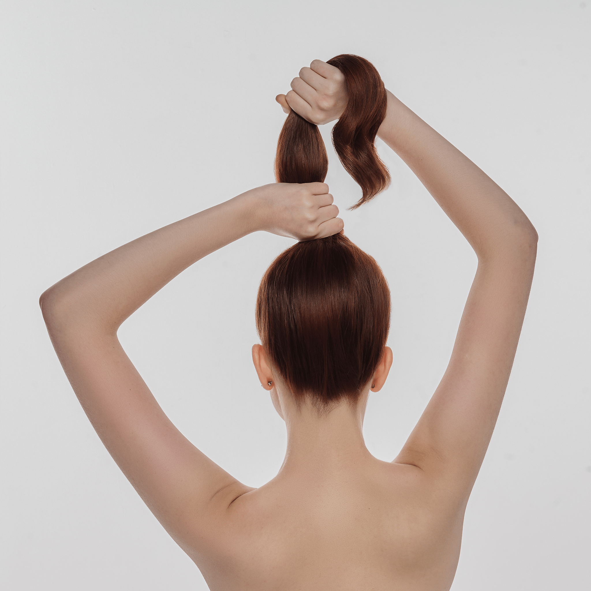 Mulher ruiva segurando o cabelo, destacando que o uso do shampoo reconstrutor fortalece os fios.