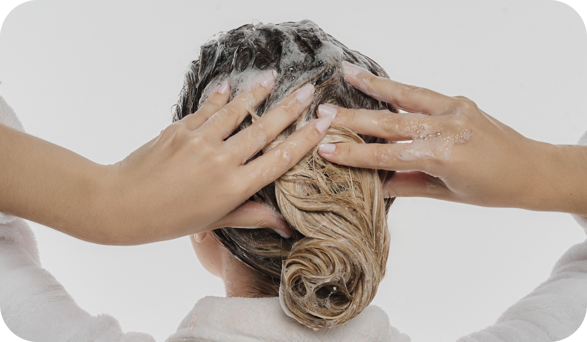 Mulher loira ensinando como limpar os fios com o Shampoo Recontutor Pro Recovery RX.