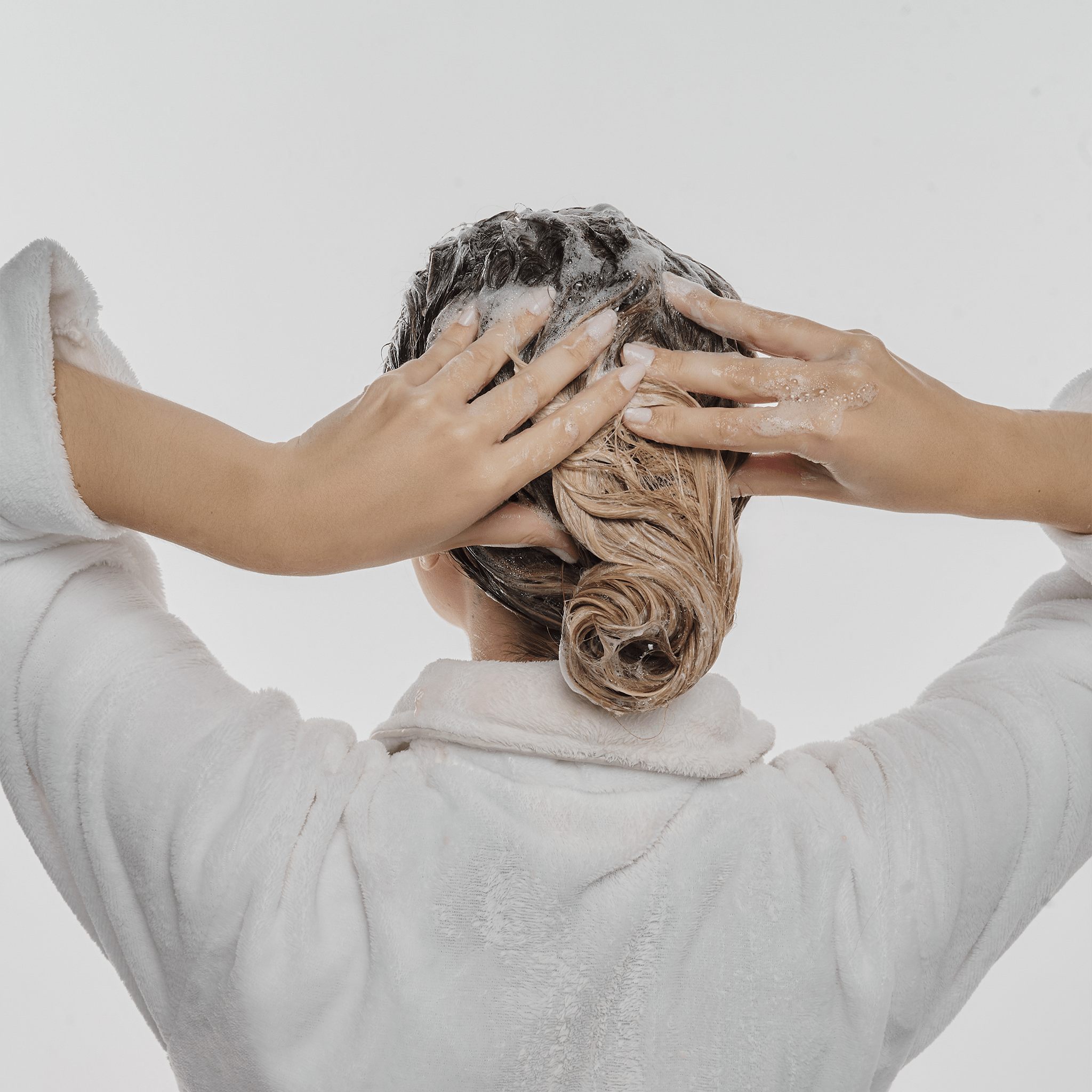 Mulher loira lavando os cabelos com o shampoo antioleosidade.
